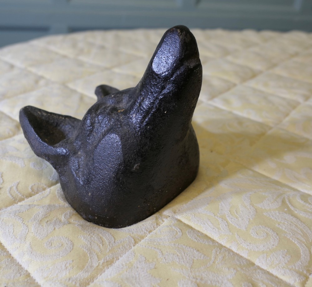 A dark cast iron doorstop sculpted in the shape of a fox head with a flat base.