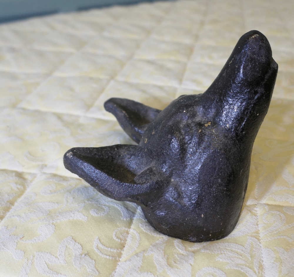 A dark cast iron doorstop sculpted in the shape of a fox head with a flat base. View III