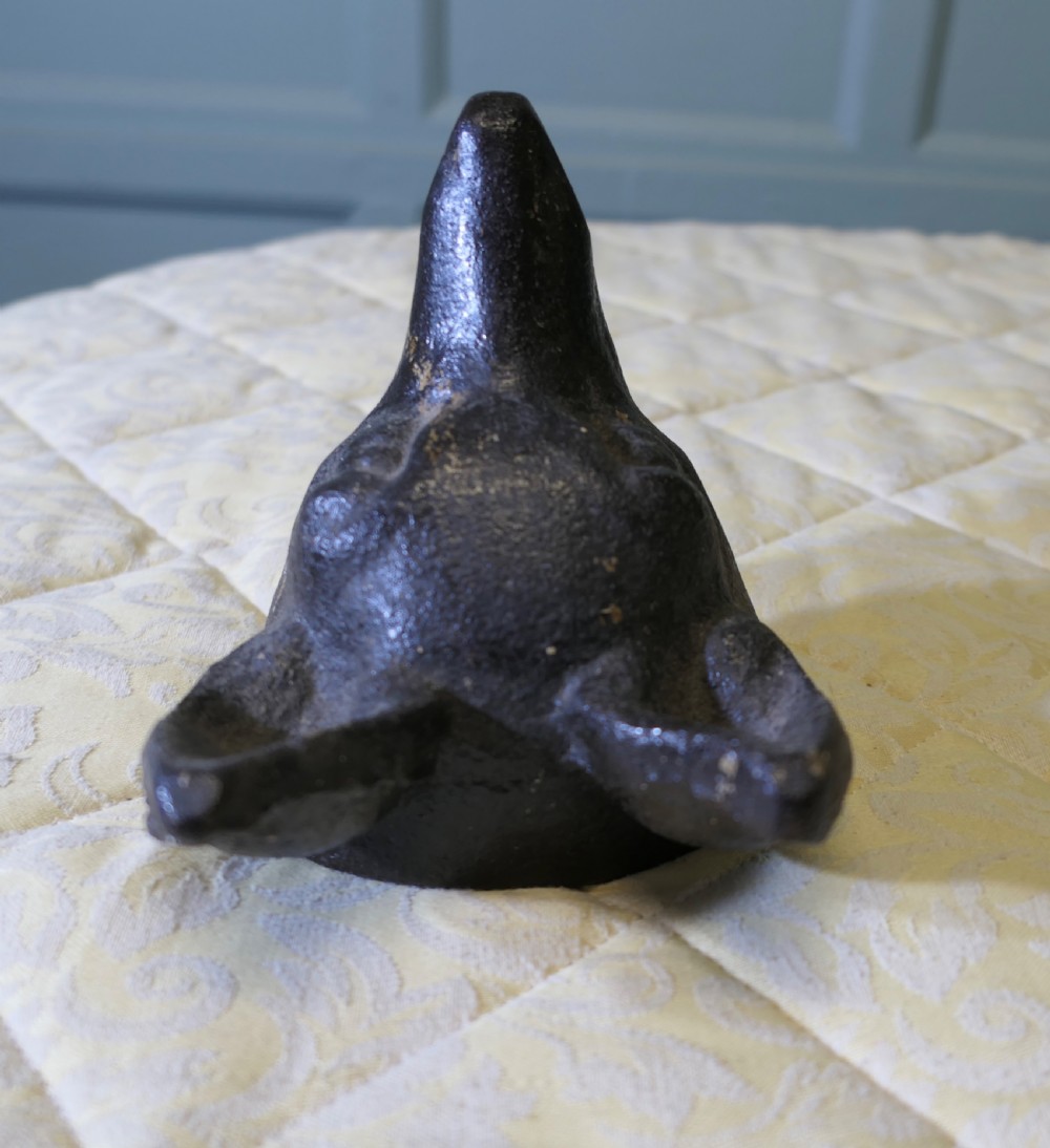 A dark cast iron doorstop sculpted in the shape of a fox head with a flat base. View V