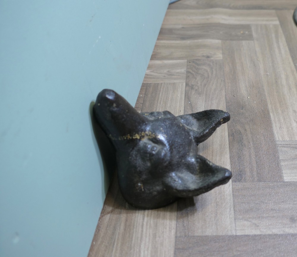 A dark cast iron doorstop sculpted in the shape of a fox head with a flat base. View VII