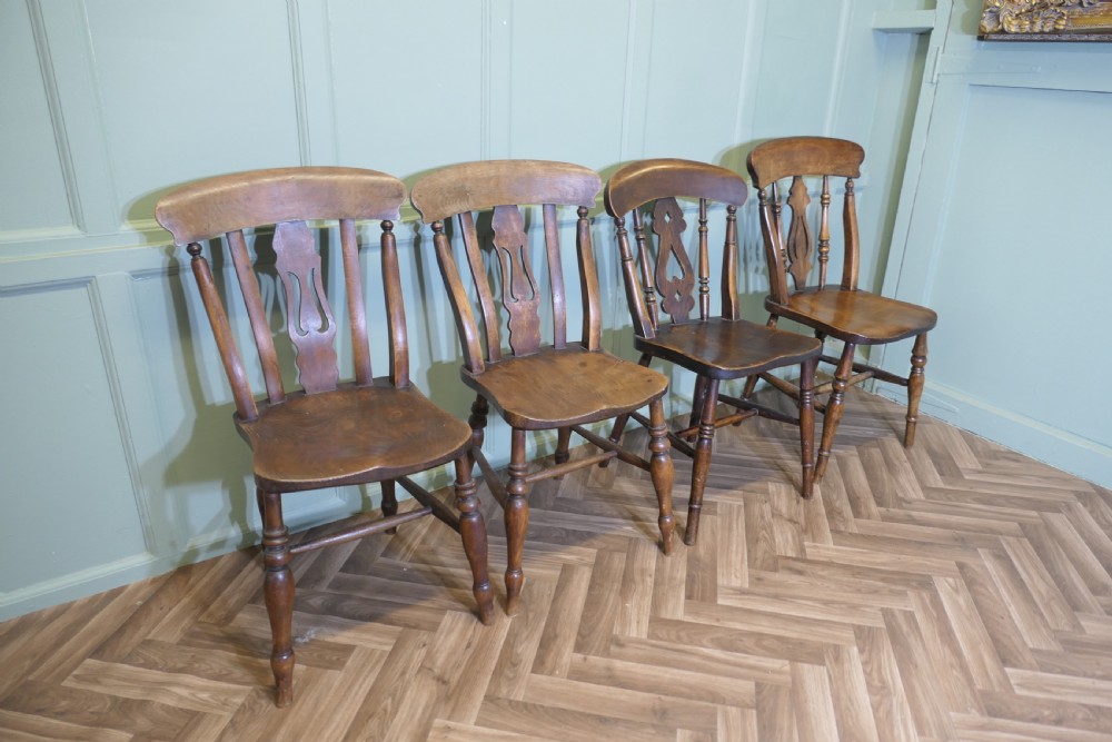 A harlequin set of four antique beech and elm dining chairs featuring shaped fiddle back splats, spindle supports, shaped wooden seats, and turned front legs. View II