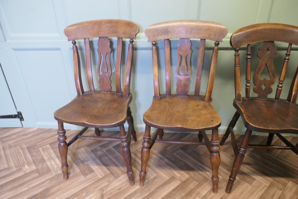 A harlequin set of four antique beech and elm dining chairs featuring shaped fiddle back splats, spindle supports, shaped wooden seats, and turned front legs. View IV