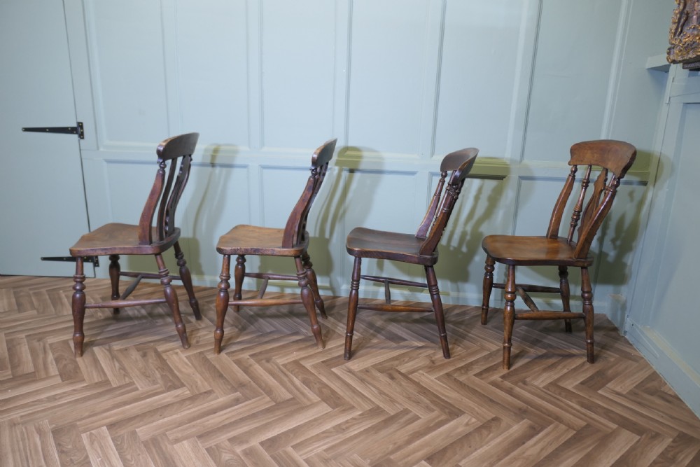 A harlequin set of four antique beech and elm dining chairs featuring shaped fiddle back splats, spindle supports, shaped wooden seats, and turned front legs. View V