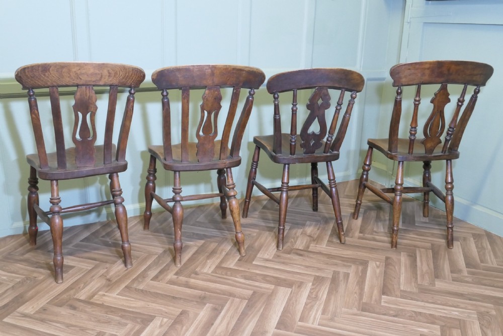 A harlequin set of four antique beech and elm dining chairs featuring shaped fiddle back splats, spindle supports, shaped wooden seats, and turned front legs. View VI