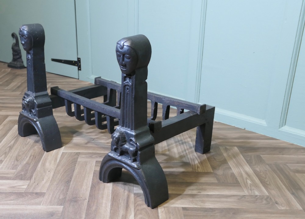 A heavy black cast iron inglenook fire grate supported by two ornate firedogs featuring sculpted relief heads and lion bases. View VII