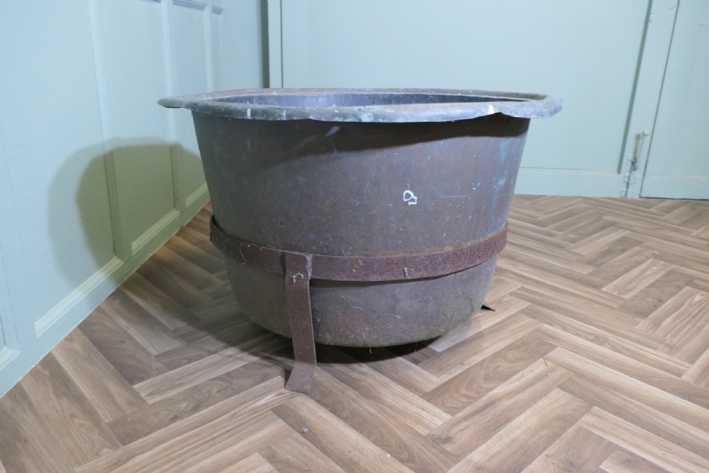 A large round patinated copper vessel with a rolled rim resting inside a dark wrought iron stand. View IV