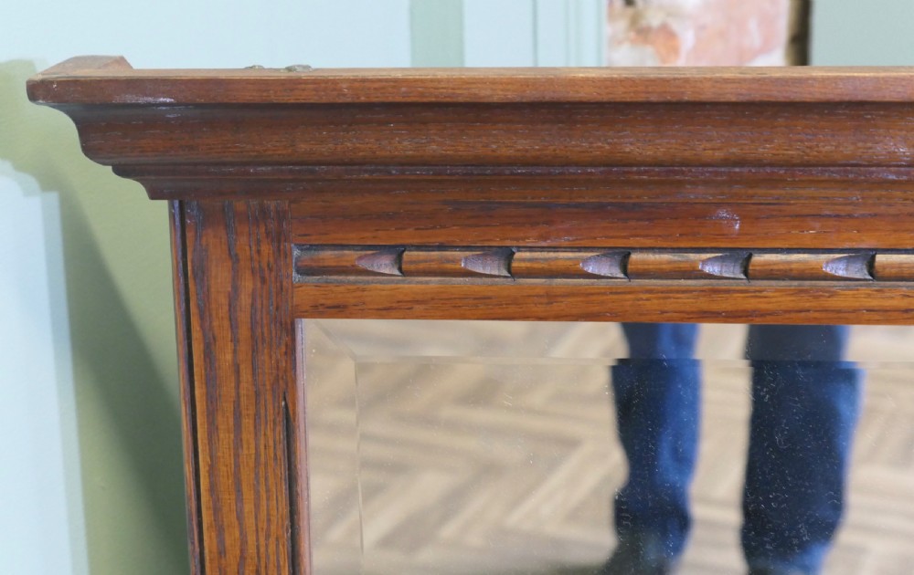 A wide dark oak overmantel frame featuring three rectangular glass mirror panels with carved moulding details along the top frieze and lower edge. View V