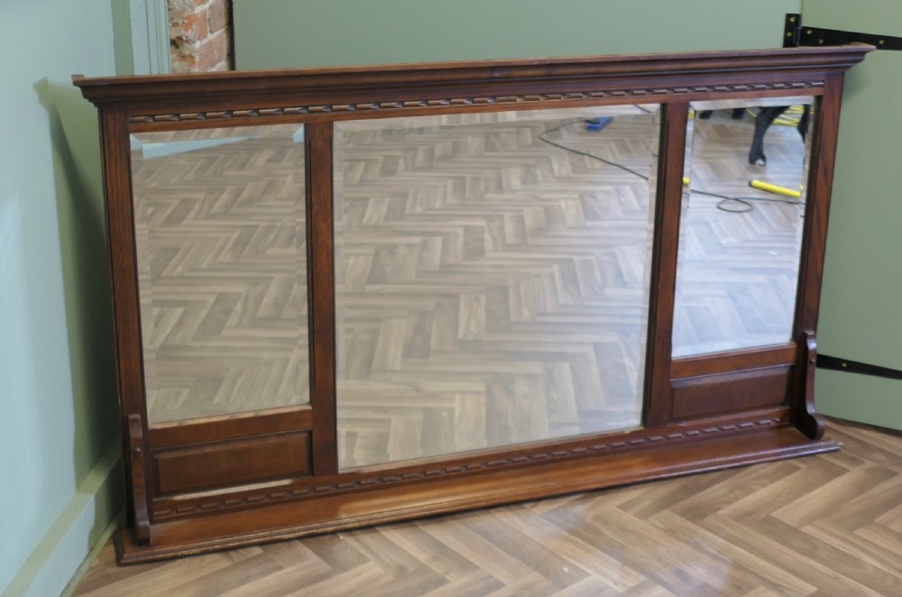 A wide dark oak overmantel frame featuring three rectangular glass mirror panels with carved moulding details along the top frieze and lower edge. View VIII