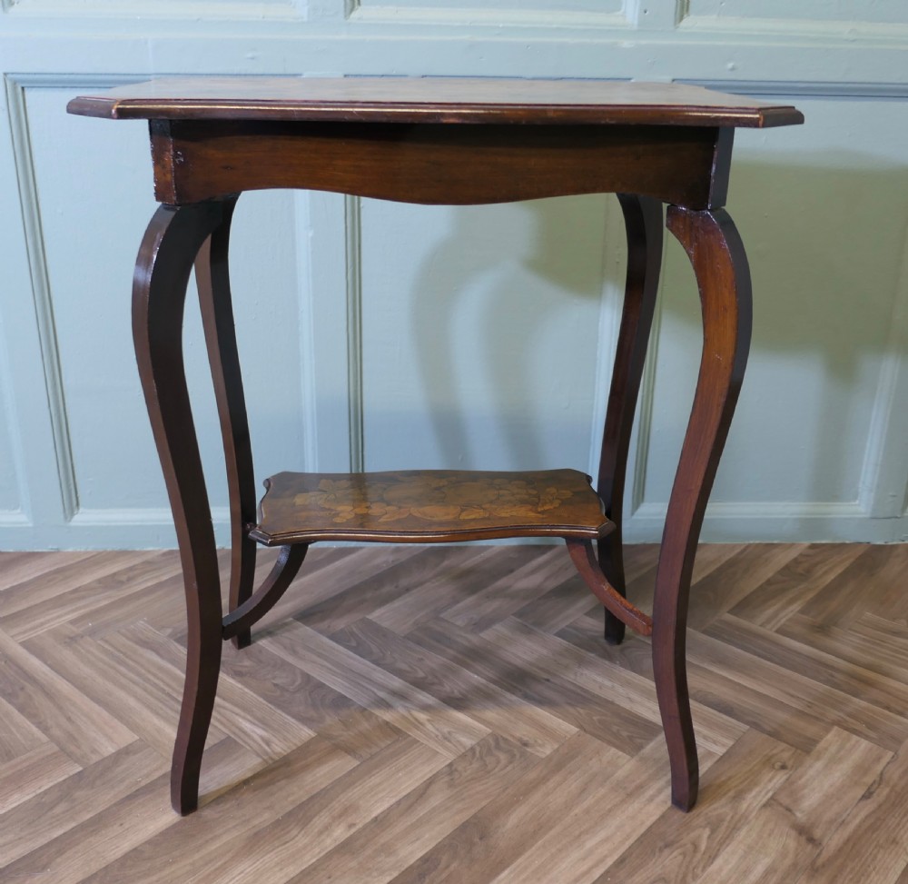 A warm brown wooden occasional table featuring a shaped serpentine top with central floral decoration, slender cabriole legs, and a decorated lower shelf. View II