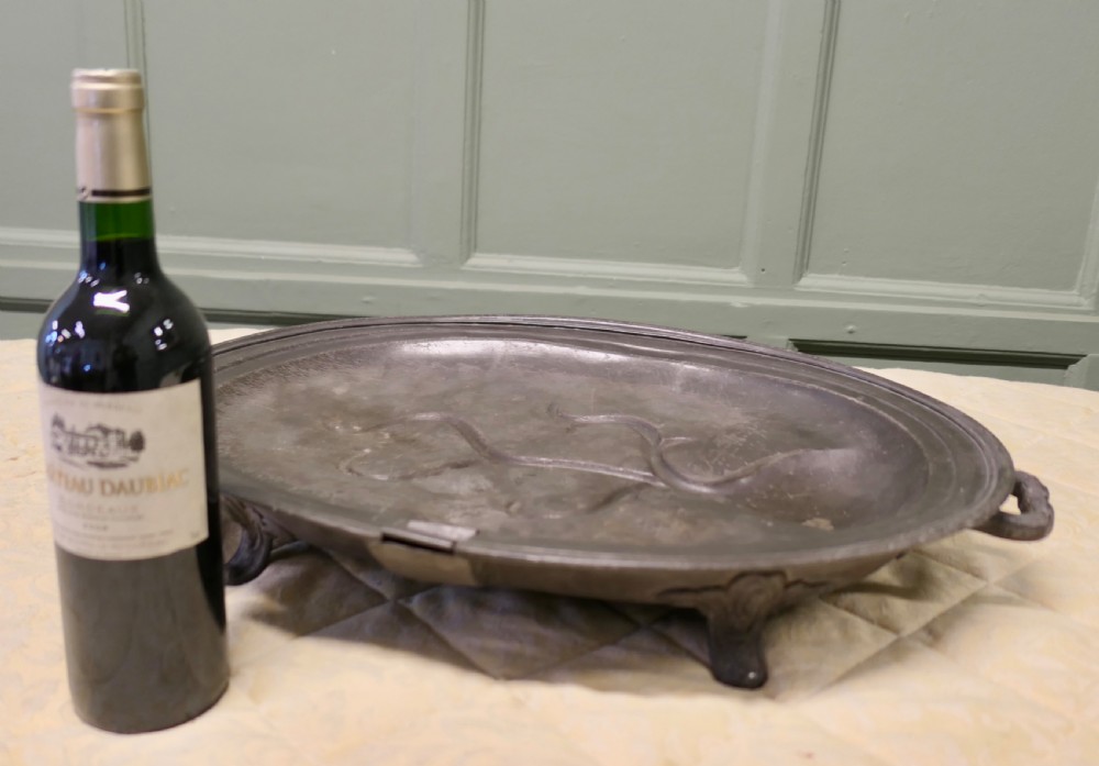 An oval antique pewter meat platter featuring raised tree-like drainage channels leading to a well at one end, flanked by a moulded rim. View III