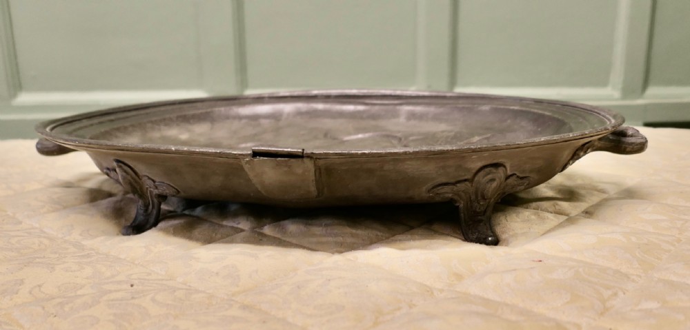 An oval antique pewter meat platter featuring raised tree-like drainage channels leading to a well at one end, flanked by a moulded rim. View IV