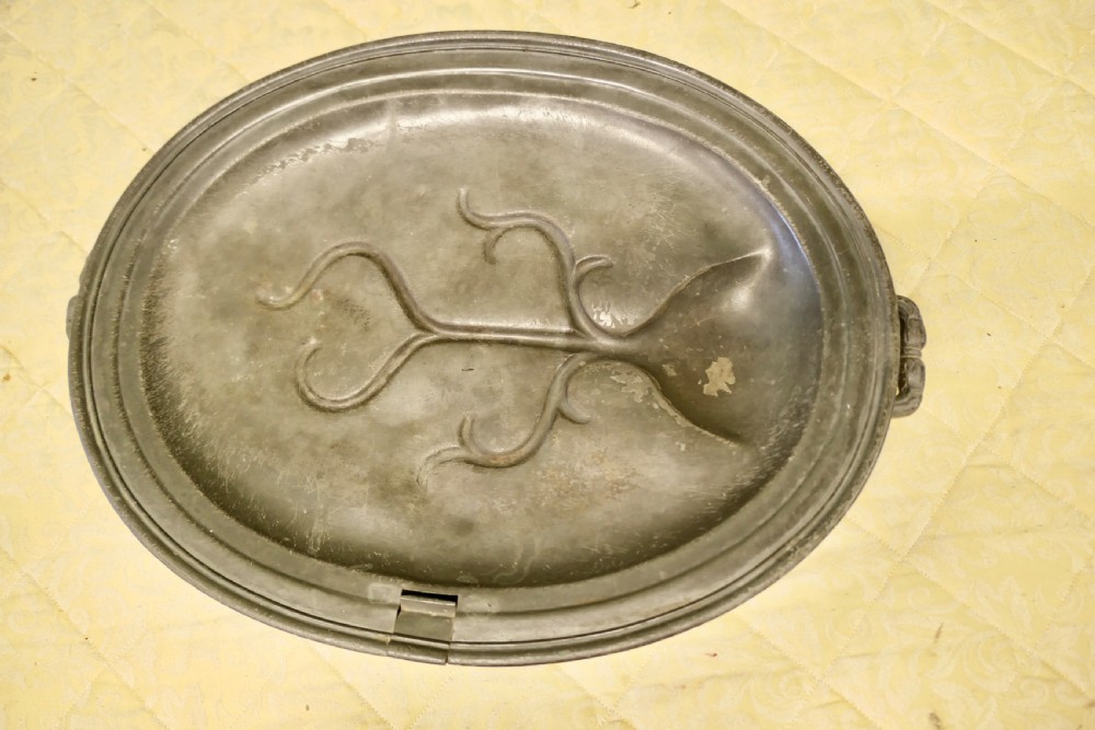 An oval antique pewter meat platter featuring raised tree-like drainage channels leading to a well at one end, flanked by a moulded rim. View VIII