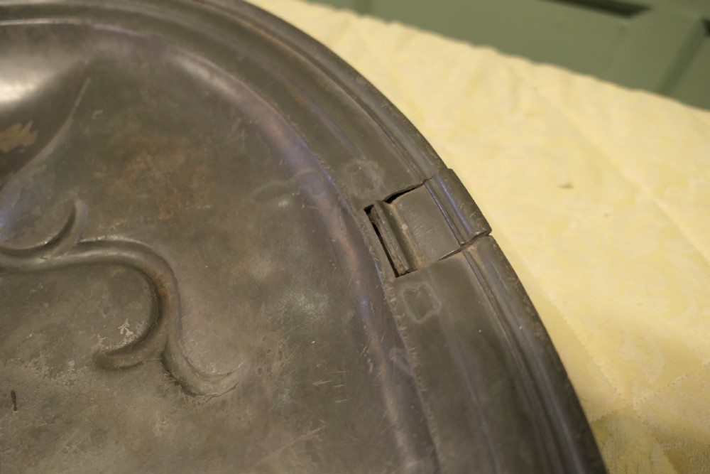 An oval antique pewter meat platter featuring raised tree-like drainage channels leading to a well at one end, flanked by a moulded rim. View X
