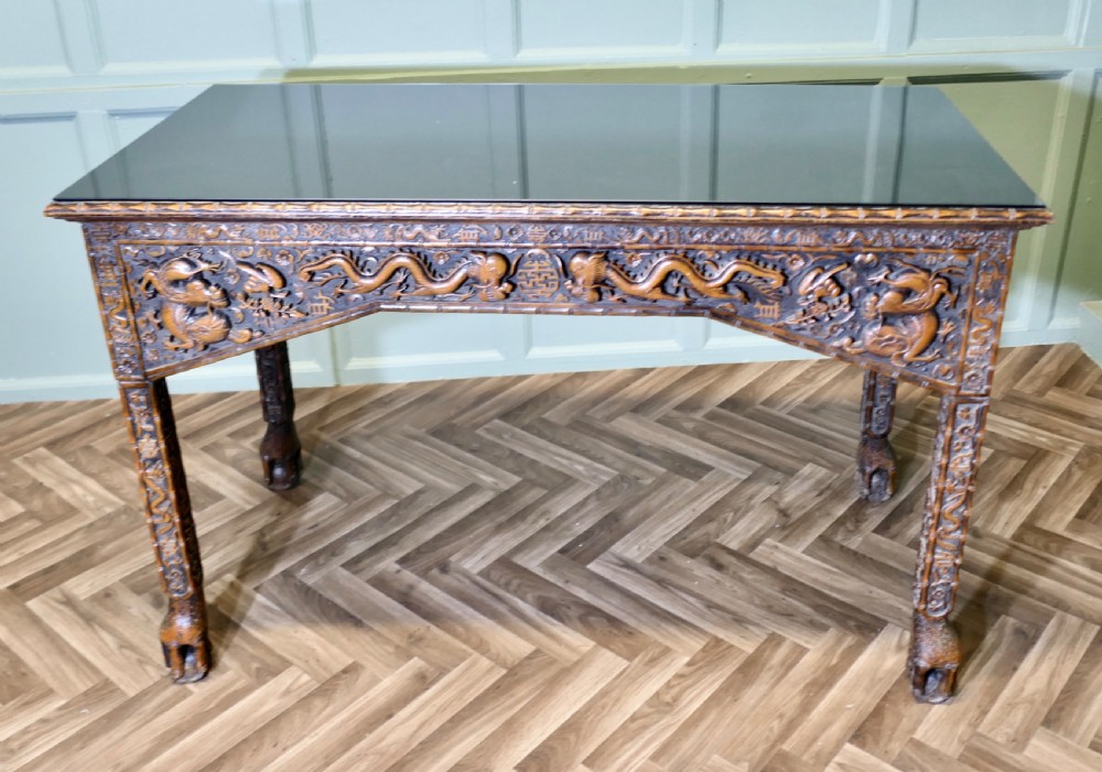 A dark brown carved wood console table featuring relief dragons on the frieze and legs with a fitted glass top. View III