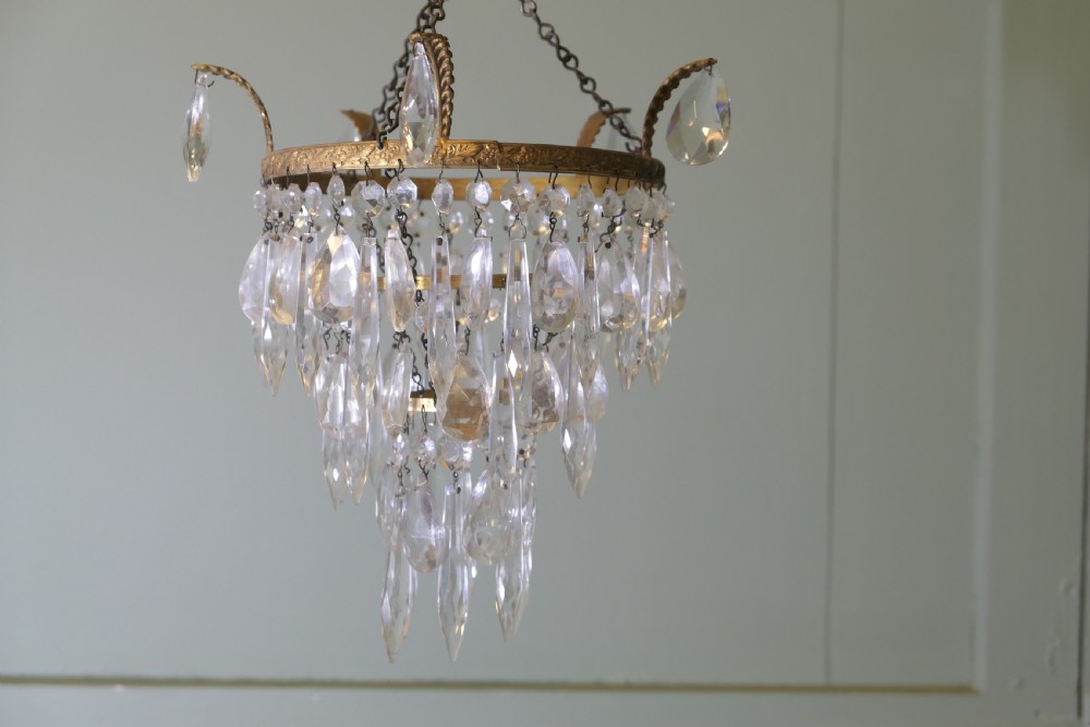 A three-tier waterfall chandelier featuring faceted glass drops suspended from an embossed brass ring with extended scroll arms. View II