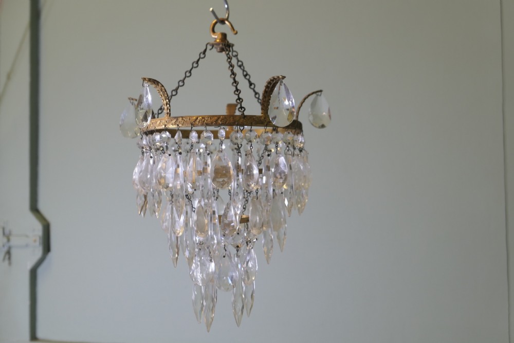 A three-tier waterfall chandelier featuring faceted glass drops suspended from an embossed brass ring with extended scroll arms. View III