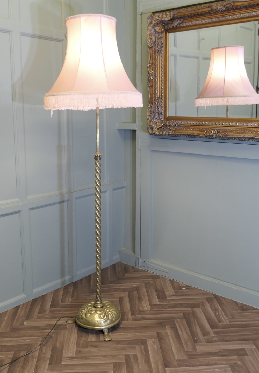 An antique brass floor lamp with a twisted column stem, adjustable height section, and a pink fabric shade with tassel fringe. View V