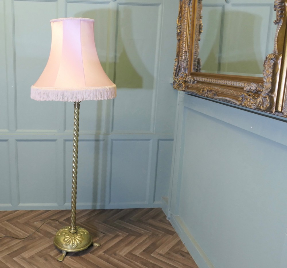 An antique brass floor lamp with a twisted column stem, adjustable height section, and a pink fabric shade with tassel fringe. View VIII