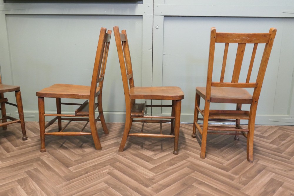 A set of eight Victorian beech and elm school chairs featuring vertical slat backs, shaped wooden seats, and turned legs with stretchers. View IV