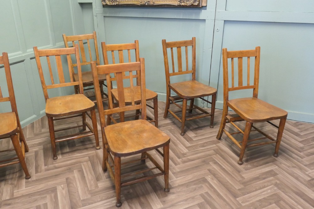 A set of eight Victorian beech and elm school chairs featuring vertical slat backs, shaped wooden seats, and turned legs with stretchers. View V