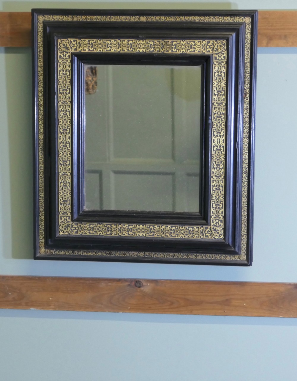 A rectangular black ebonised wall mirror featuring ornate gilt brass chased mounts along its frame. View III