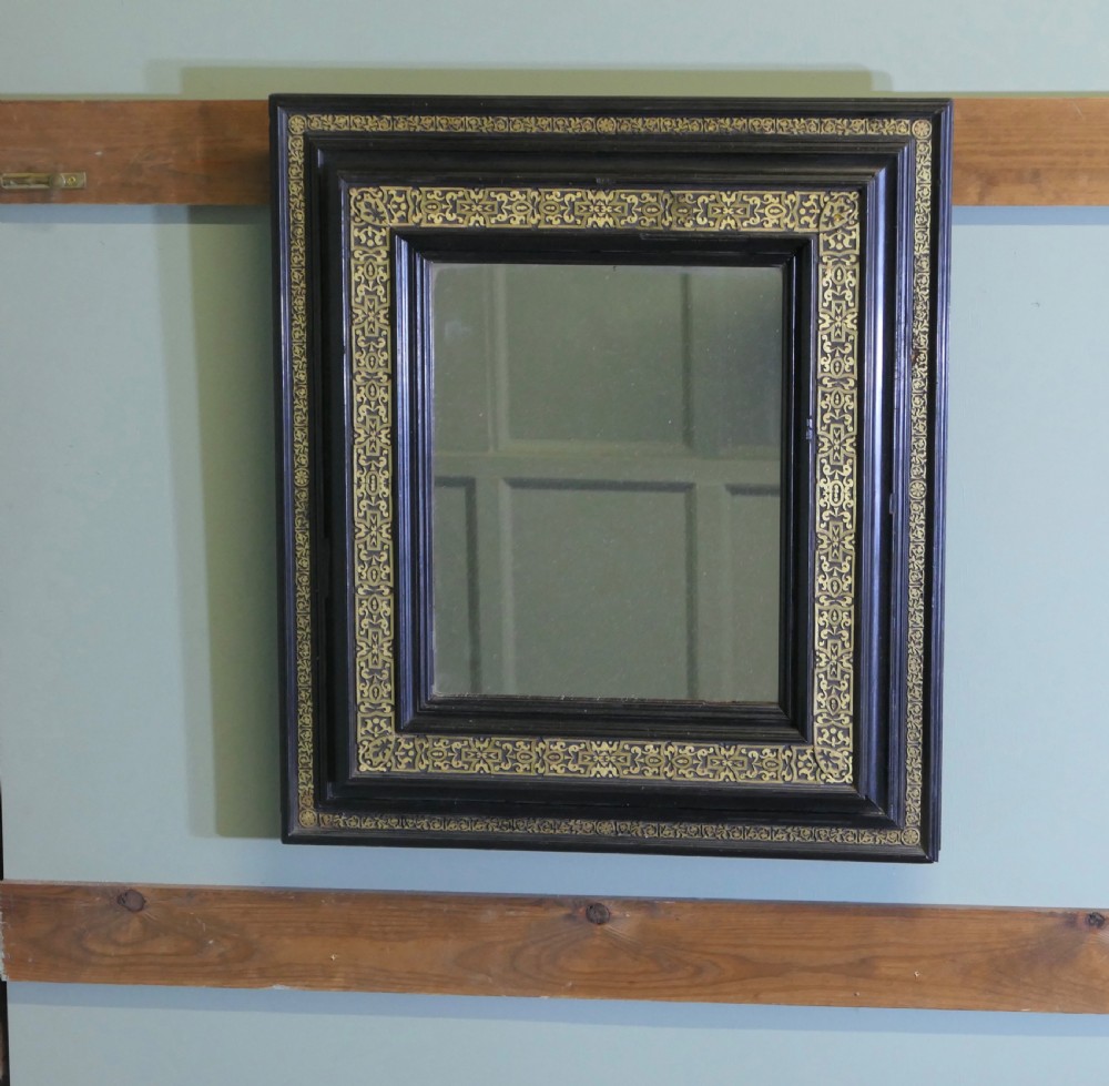 A rectangular black ebonised wall mirror featuring ornate gilt brass chased mounts along its frame. View IV