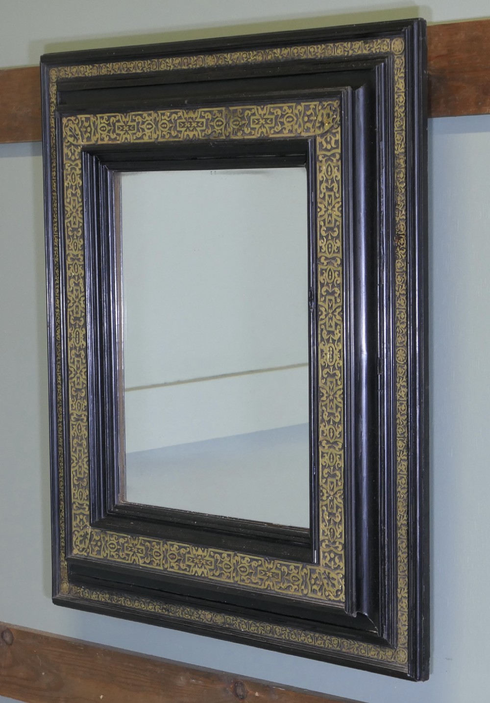 A rectangular black ebonised wall mirror featuring ornate gilt brass chased mounts along its frame. View V