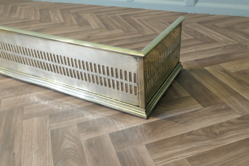 A long 19th-century brass fireplace fender featuring two rows of vertical pierced fretwork slots along its front panel. View III