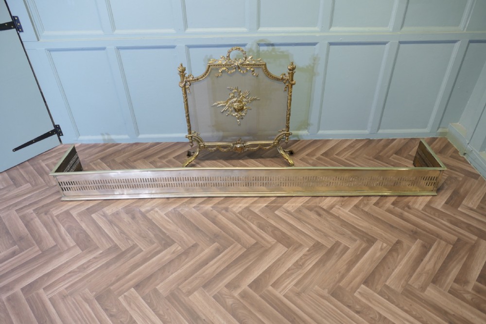 A long 19th-century brass fireplace fender featuring two rows of vertical pierced fretwork slots along its front panel. View VI