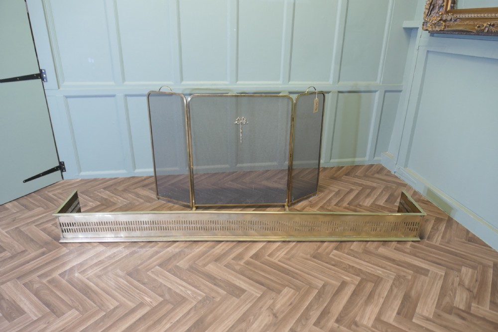 A long 19th-century brass fireplace fender featuring two rows of vertical pierced fretwork slots along its front panel. View VIII