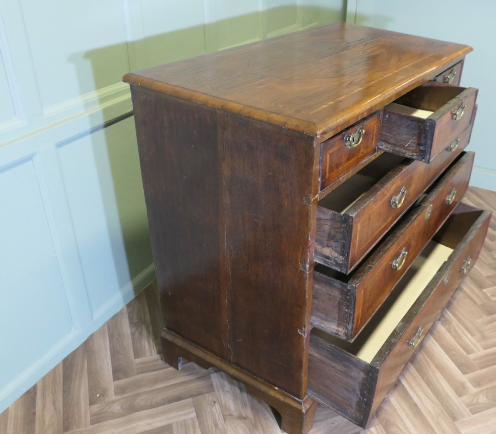 An 18th-century chest of drawers featuring inlaid walnut and satinwood crossbanding with brass drop handles and bracket feet. View V