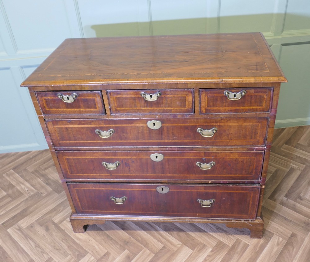 An 18th-century chest of drawers featuring inlaid walnut and satinwood crossbanding with brass drop handles and bracket feet. View VI