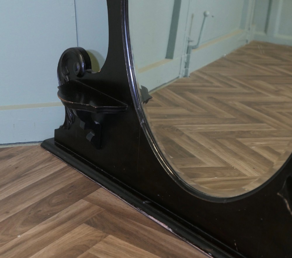 An Edwardian black lacquered overmantel mirror featuring a central heart-shaped glass plate, carved leaf crest, and two integrated side display shelves. View IV