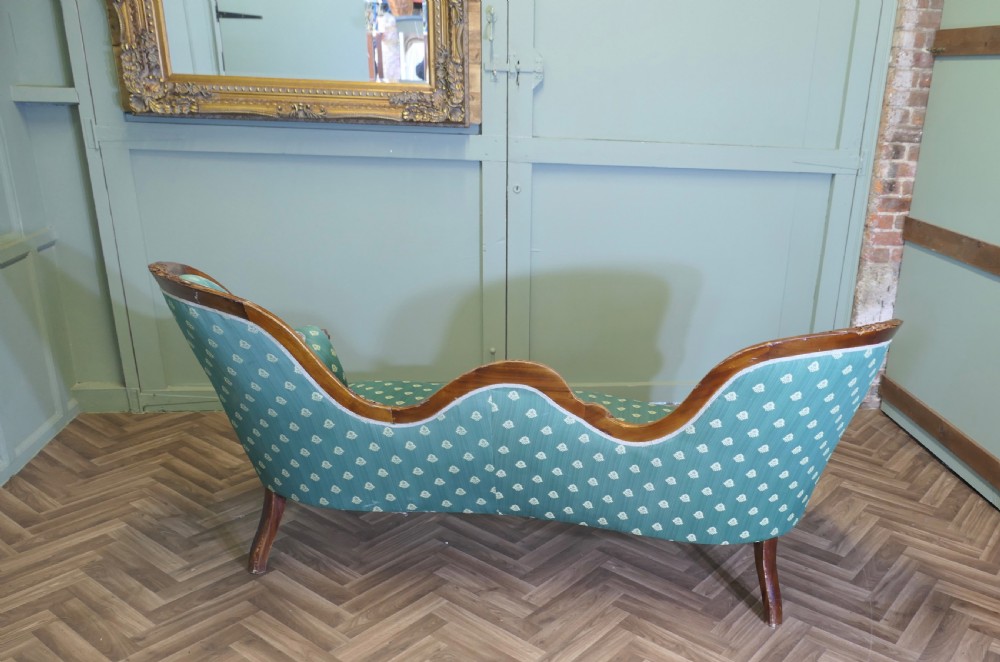 A Victorian double spoon-back settee featuring a polished mahogany frame with deep-buttoned green patterned fabric upholstery. View V