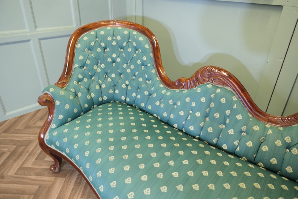 A Victorian double spoon-back settee featuring a polished mahogany frame with deep-buttoned green patterned fabric upholstery. View VII