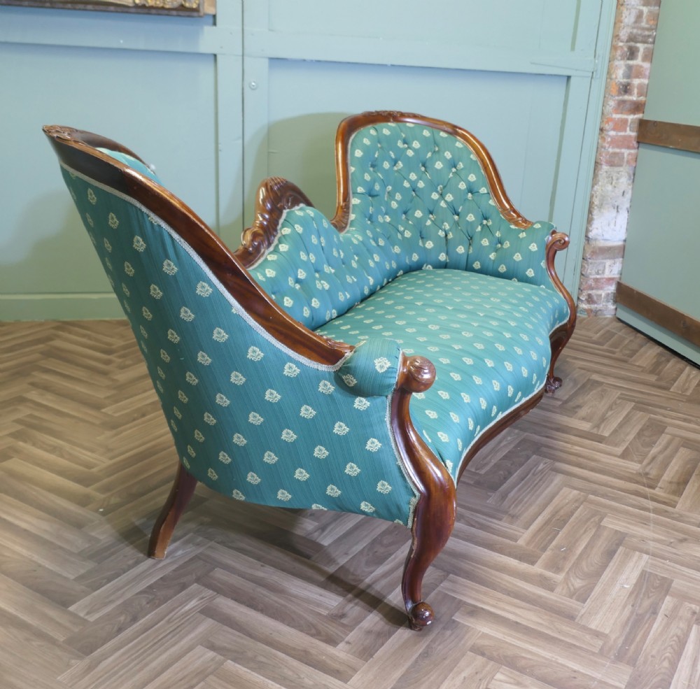 A Victorian double spoon-back settee featuring a polished mahogany frame with deep-buttoned green patterned fabric upholstery. View IX