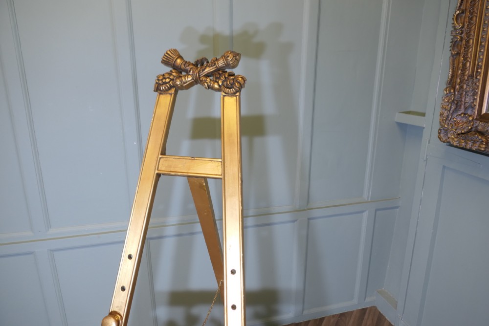 A tall French carved giltwood floor easel featuring floral swags, a top cresting motif, and scrolled feet. View VIII