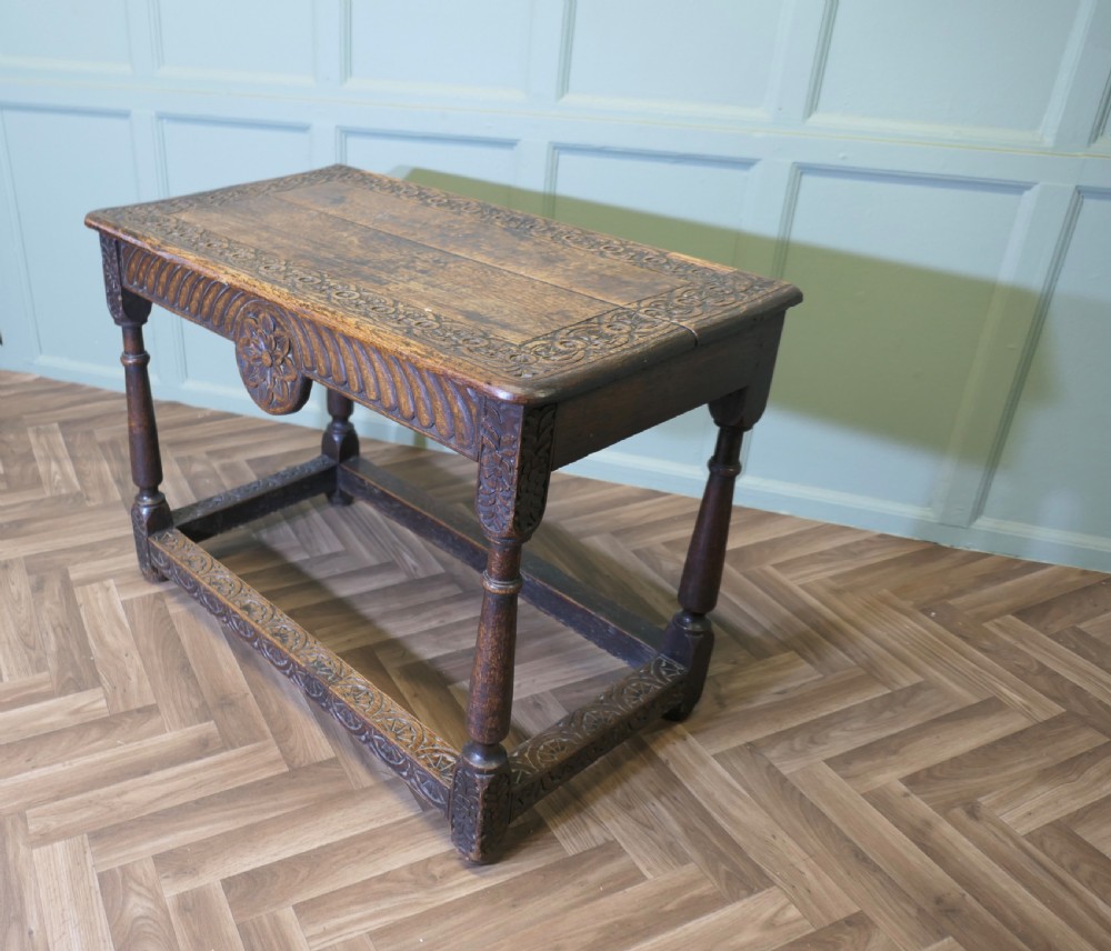 A dark oak rectangular occasional table with hand-carved Celtic knotwork detailing, a relief carved apron, turned legs, and lower stretchers.