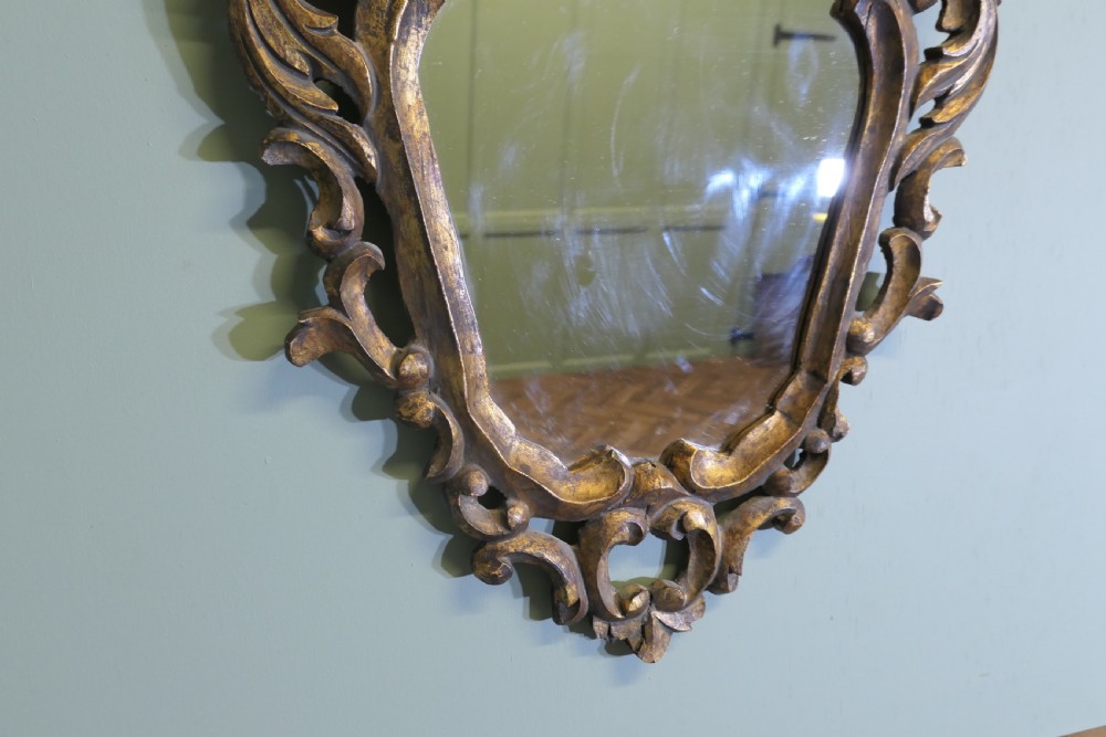 An ornate Baroque style small wall mirror featuring a carved gold leaf frame with elaborate acanthus scrollwork and cresting. View IV