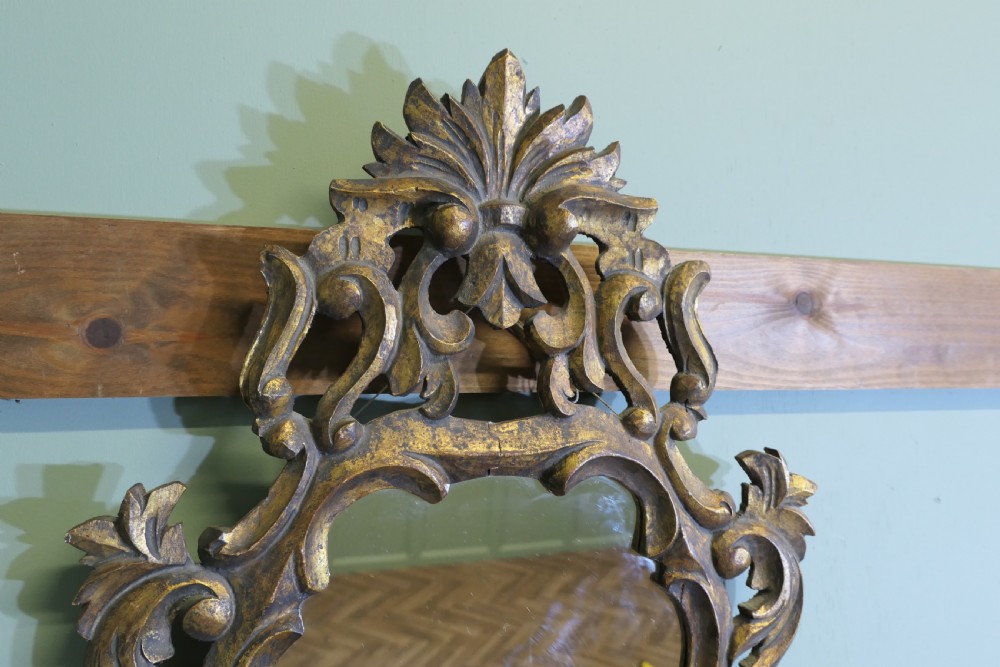 An ornate Baroque style small wall mirror featuring a carved gold leaf frame with elaborate acanthus scrollwork and cresting. View VII