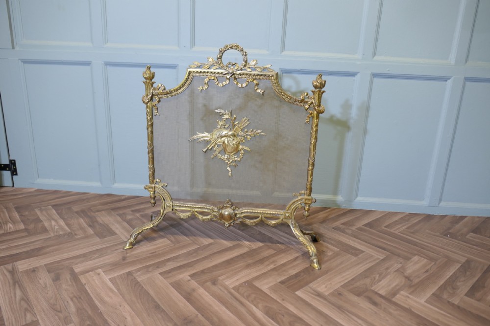 An ornate French gilded brass fire screen featuring intricate floral swags, a central bow motif, fine mesh panel, and decorative cabriole feet. View II