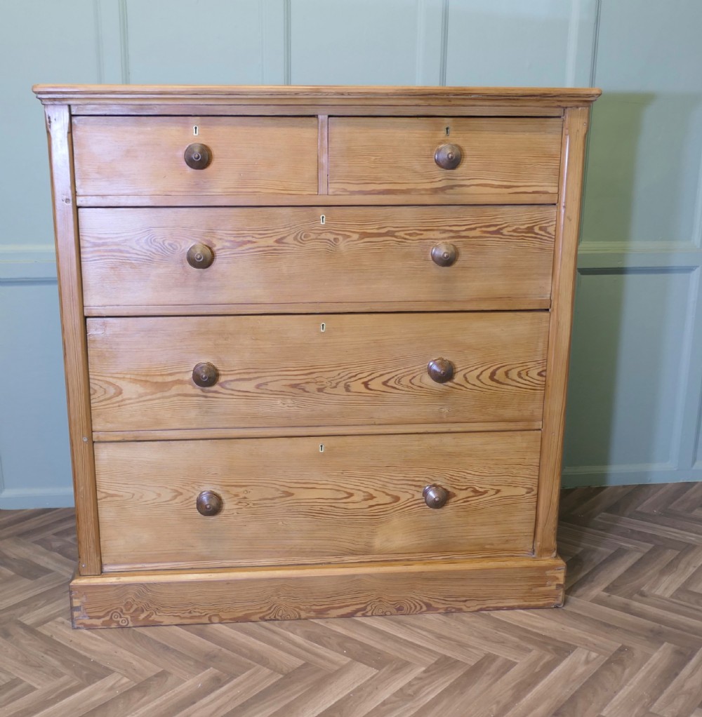 A Victorian stripped pine chest of drawers in a two-over-three arrangement with turned wooden knobs and a solid plinth base. View II