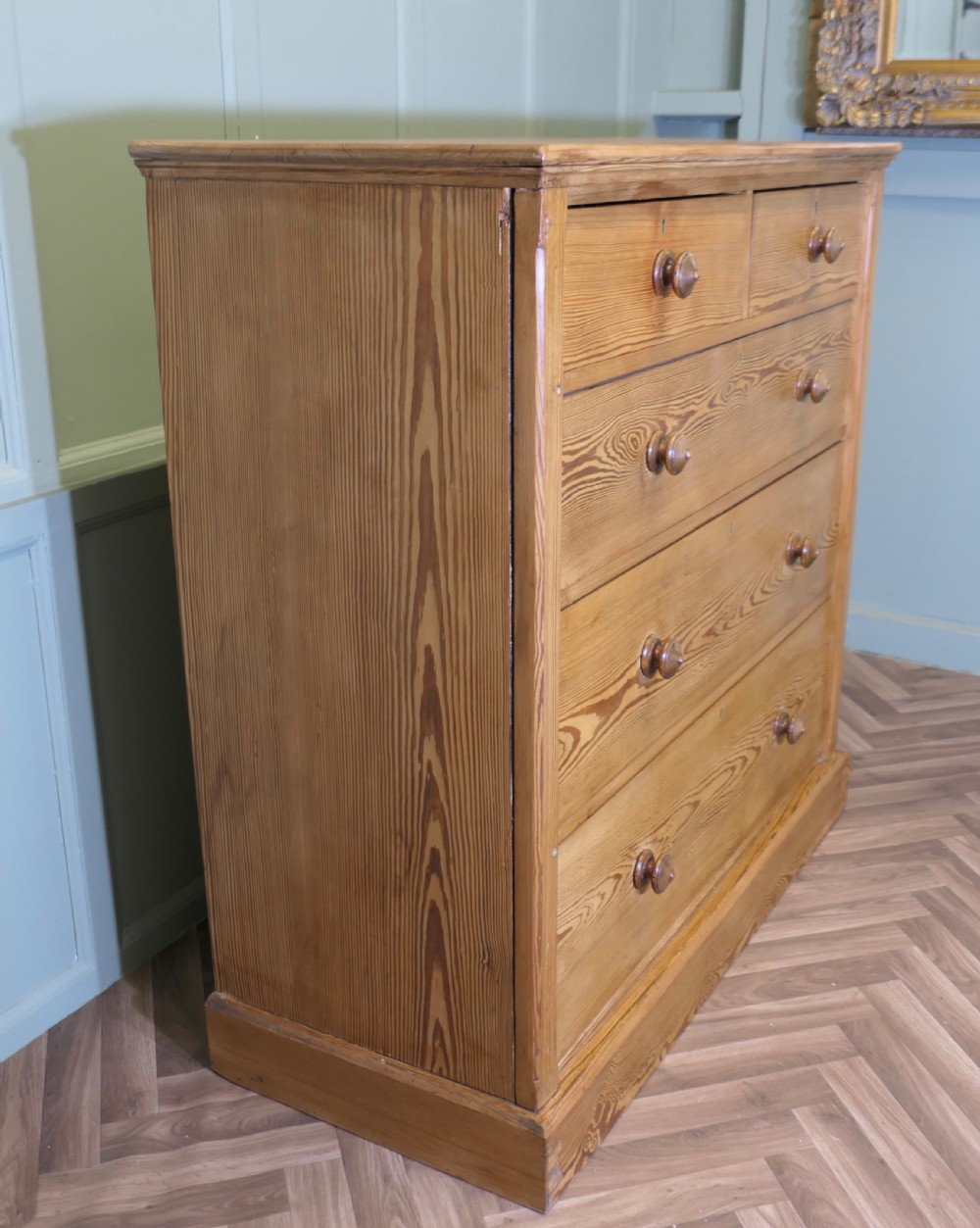 A Victorian stripped pine chest of drawers in a two-over-three arrangement with turned wooden knobs and a solid plinth base. View V