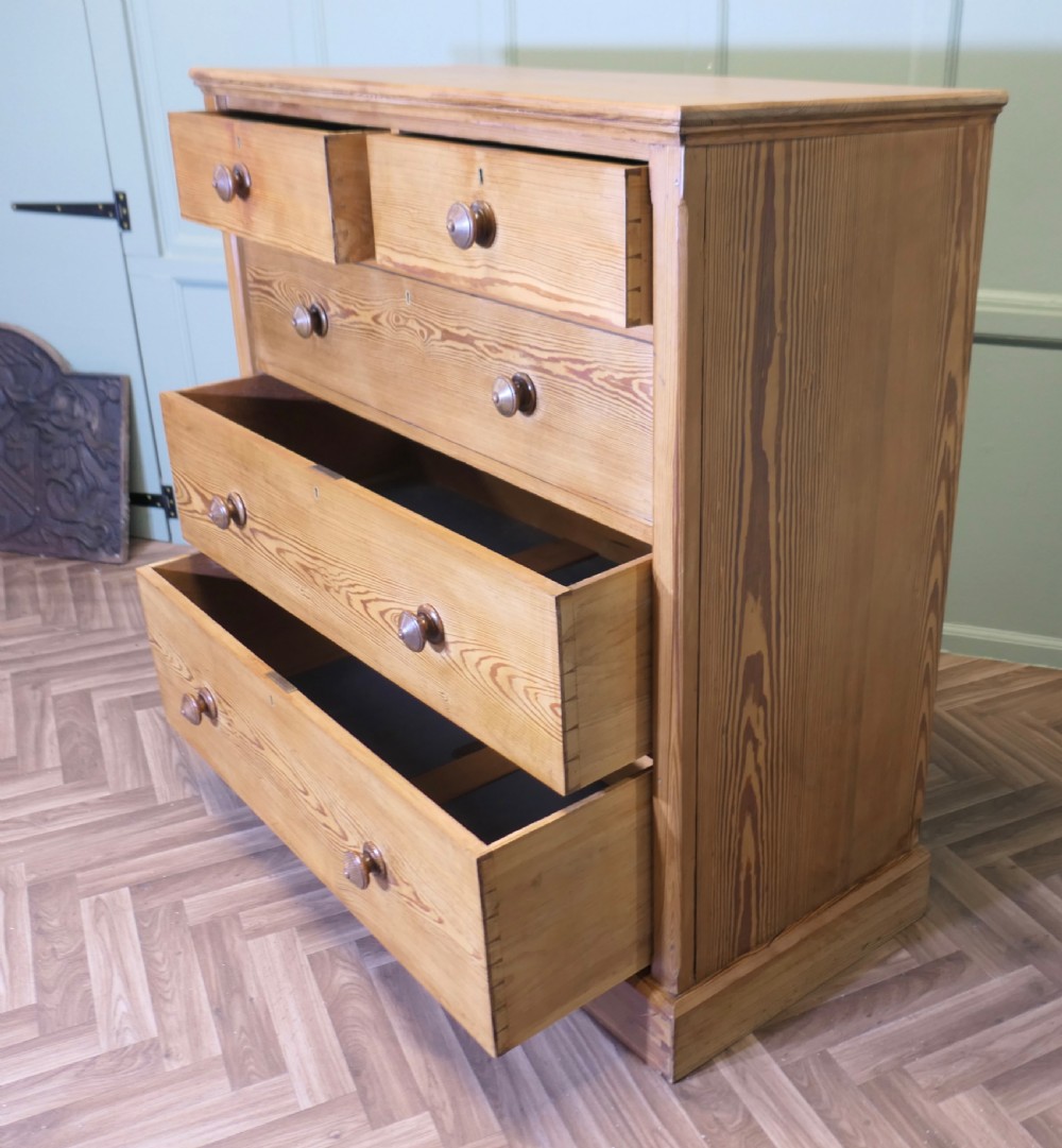 A Victorian stripped pine chest of drawers in a two-over-three arrangement with turned wooden knobs and a solid plinth base. View VI
