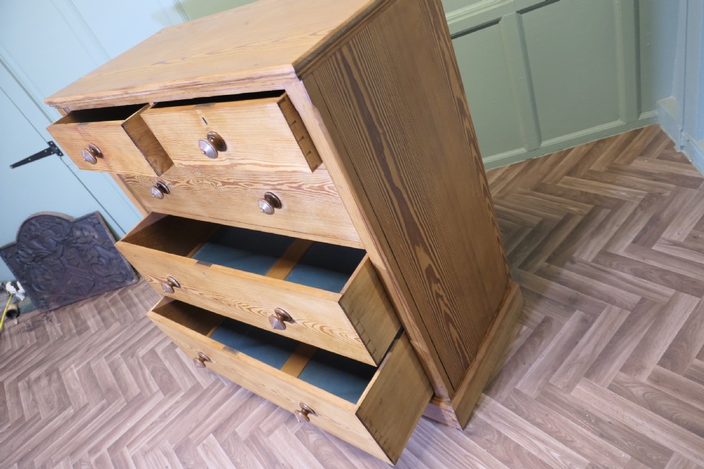 A Victorian stripped pine chest of drawers in a two-over-three arrangement with turned wooden knobs and a solid plinth base. View VII