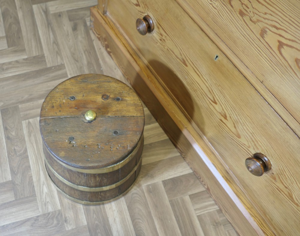 A cylindrical staved oak grog tub bound with three brass bands and fitted with a flat wooden lid with a central brass finial.