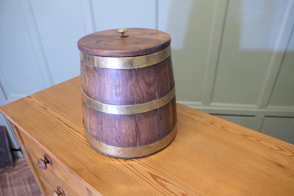 A cylindrical staved oak grog tub bound with three brass bands and fitted with a flat wooden lid with a central brass finial. View II