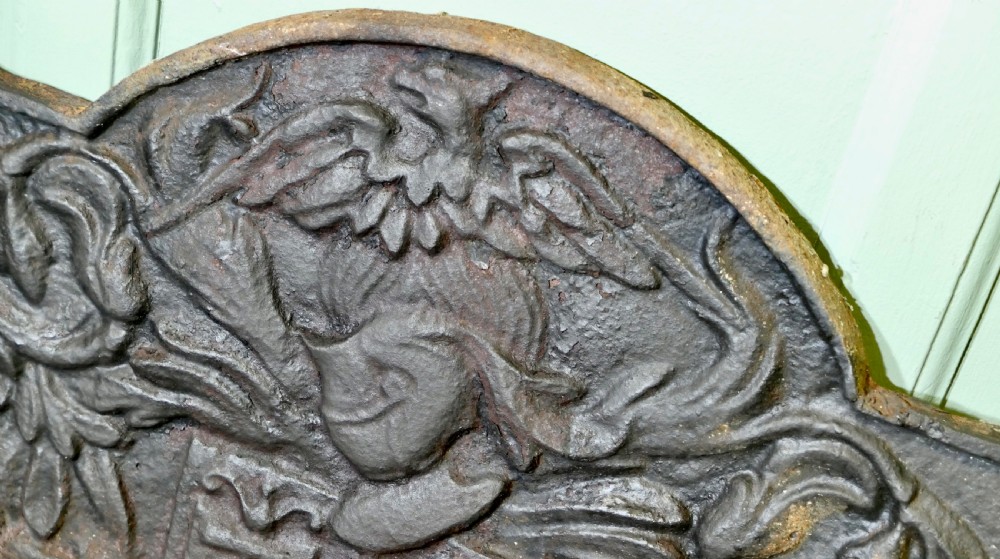 A 17th-century arched cast iron fireback displaying a heraldic crest, a knights helmet with foliage mantling, an eagle, and the date 1650. View II