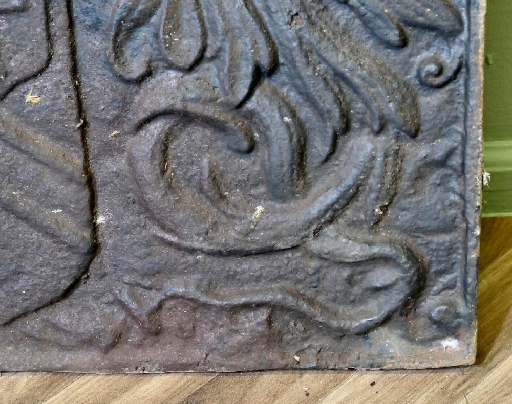 A 17th-century arched cast iron fireback displaying a heraldic crest, a knights helmet with foliage mantling, an eagle, and the date 1650. View VI