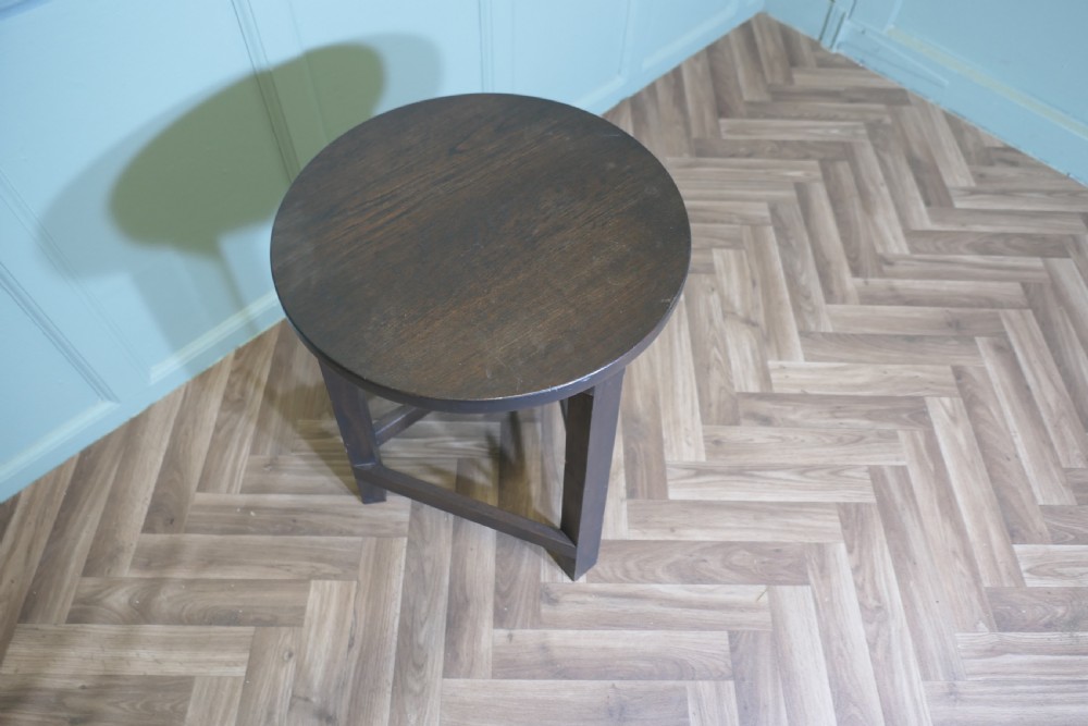 A dark-stained English oak cricket table featuring a circular top supported by three straight legs joined by a lower triangular stretcher. View III